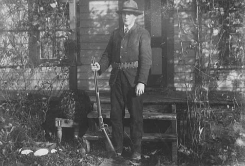 Man standing with gun and ammunition belt